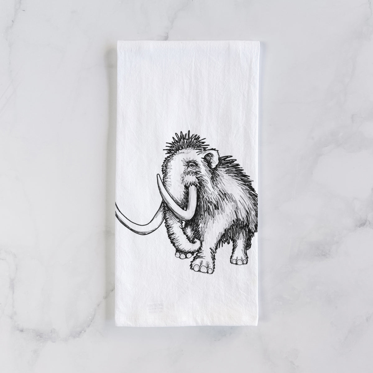 White cotton tea towel laid flat on marble, printed with a black ink illustration of a woolly mammoth with long curved tusks.
