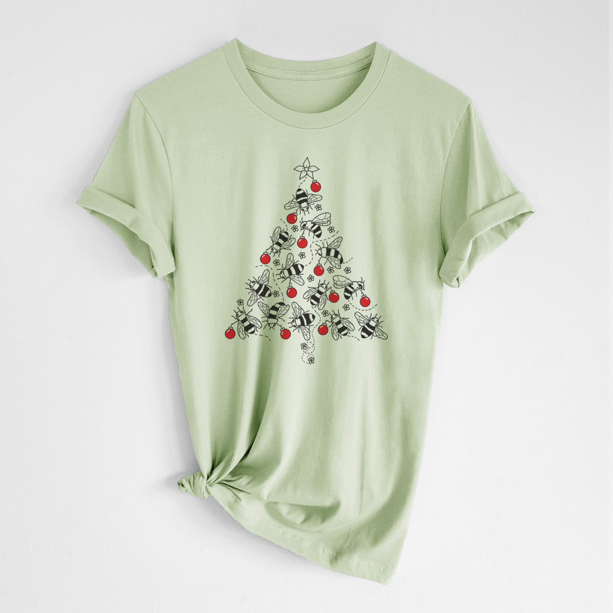 Spring green lightweight cotton t-shirt laid flat with the sleeves rolled, printed with a Christmas tree made of black ink bees with red ornaments and a star on top.