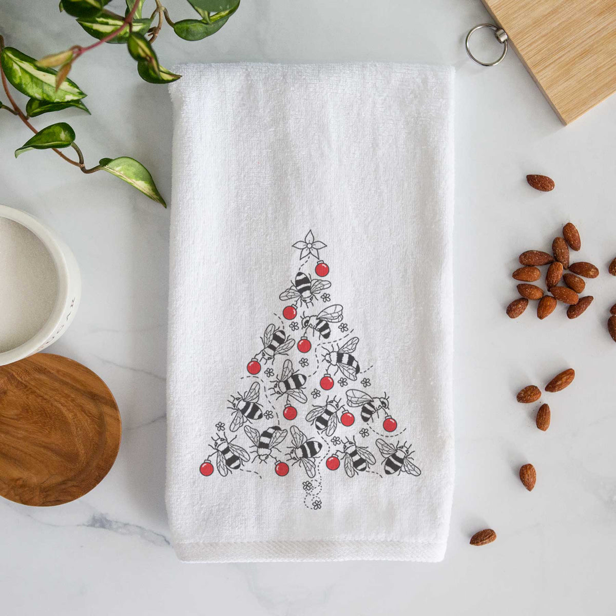 White hand towel printed with a Christmas tree made of black ink bees with red ornaments and a star on top.