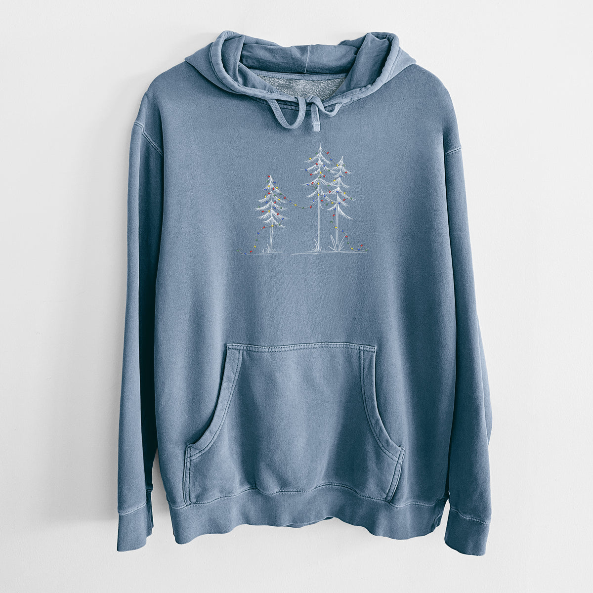 Slate blue pigment dyed hoodie laid flat, printed with three slender white ink pine trees strung with a garland of multicolored holiday lights.