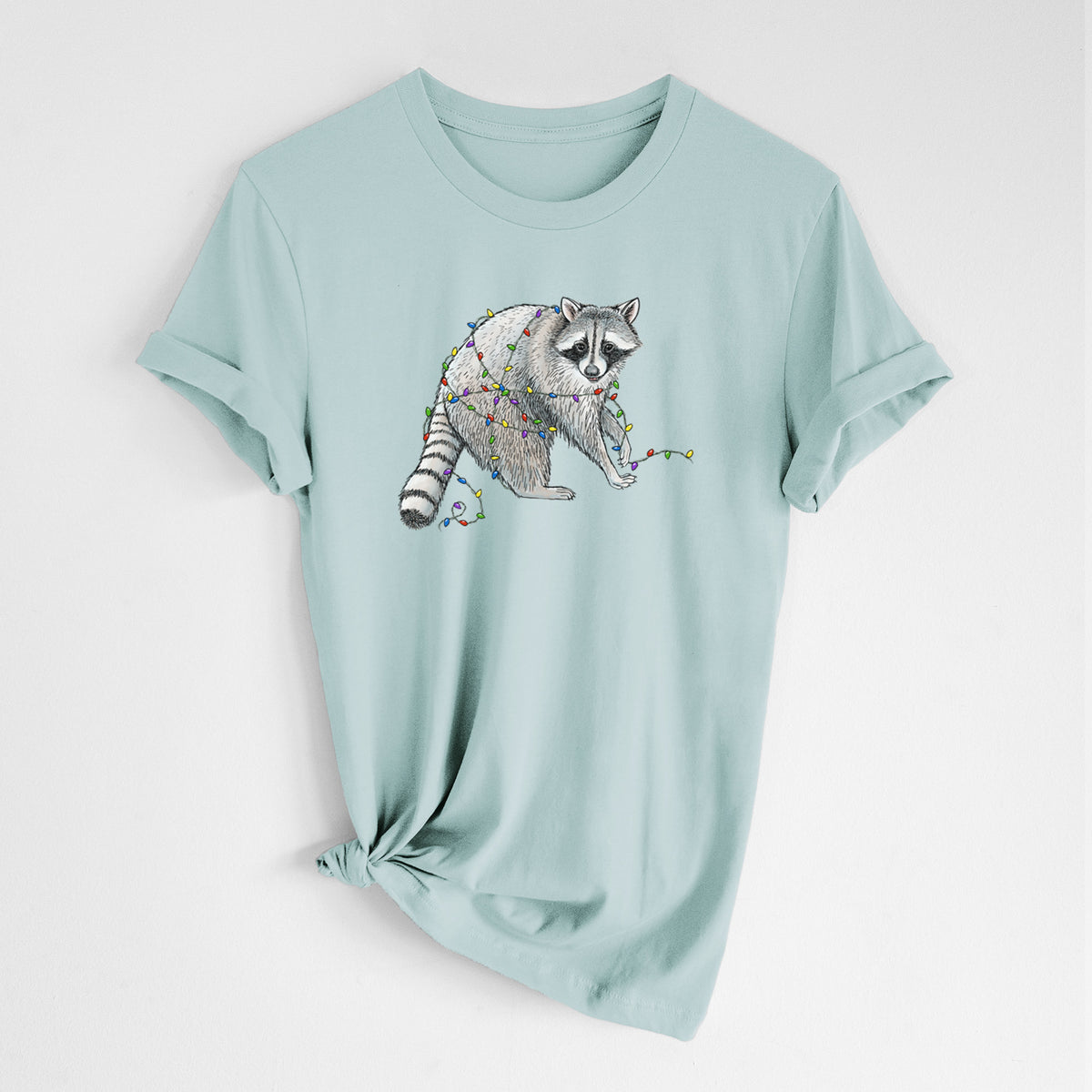 Dusty blue lightweight cotton t-shirt laid flat with the sleeves rolled, printed with a black ink raccoon tangled in a string of colorful holiday lights.