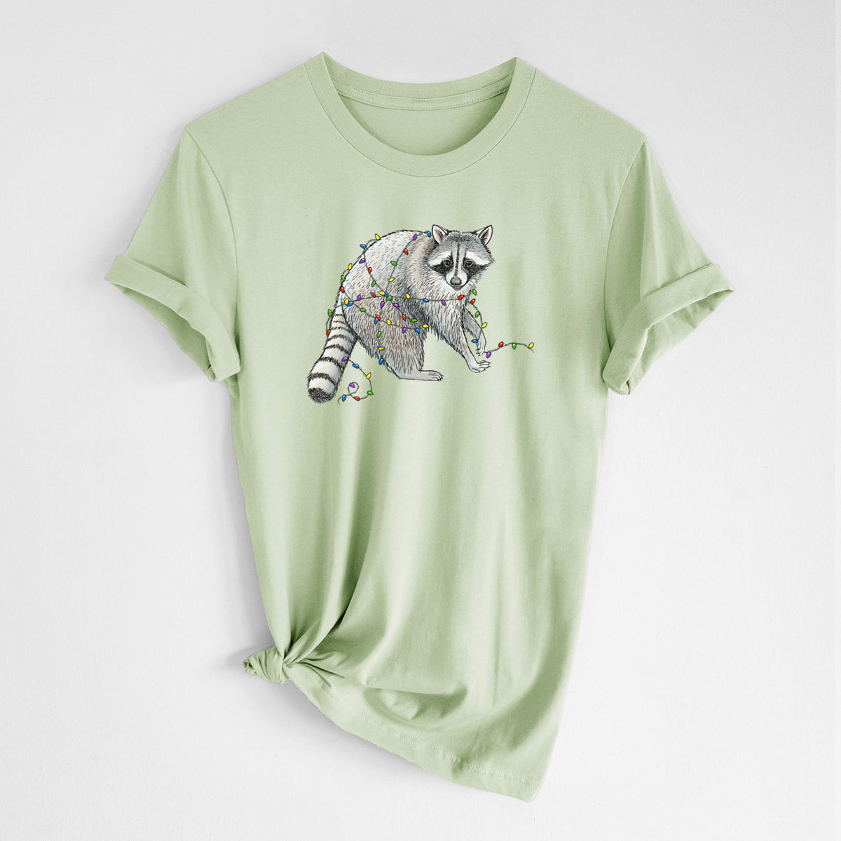 Spring green lightweight cotton t-shirt laid flat with the sleeves rolled, printed with a black ink raccoon tangled in a string of colorful holiday lights.