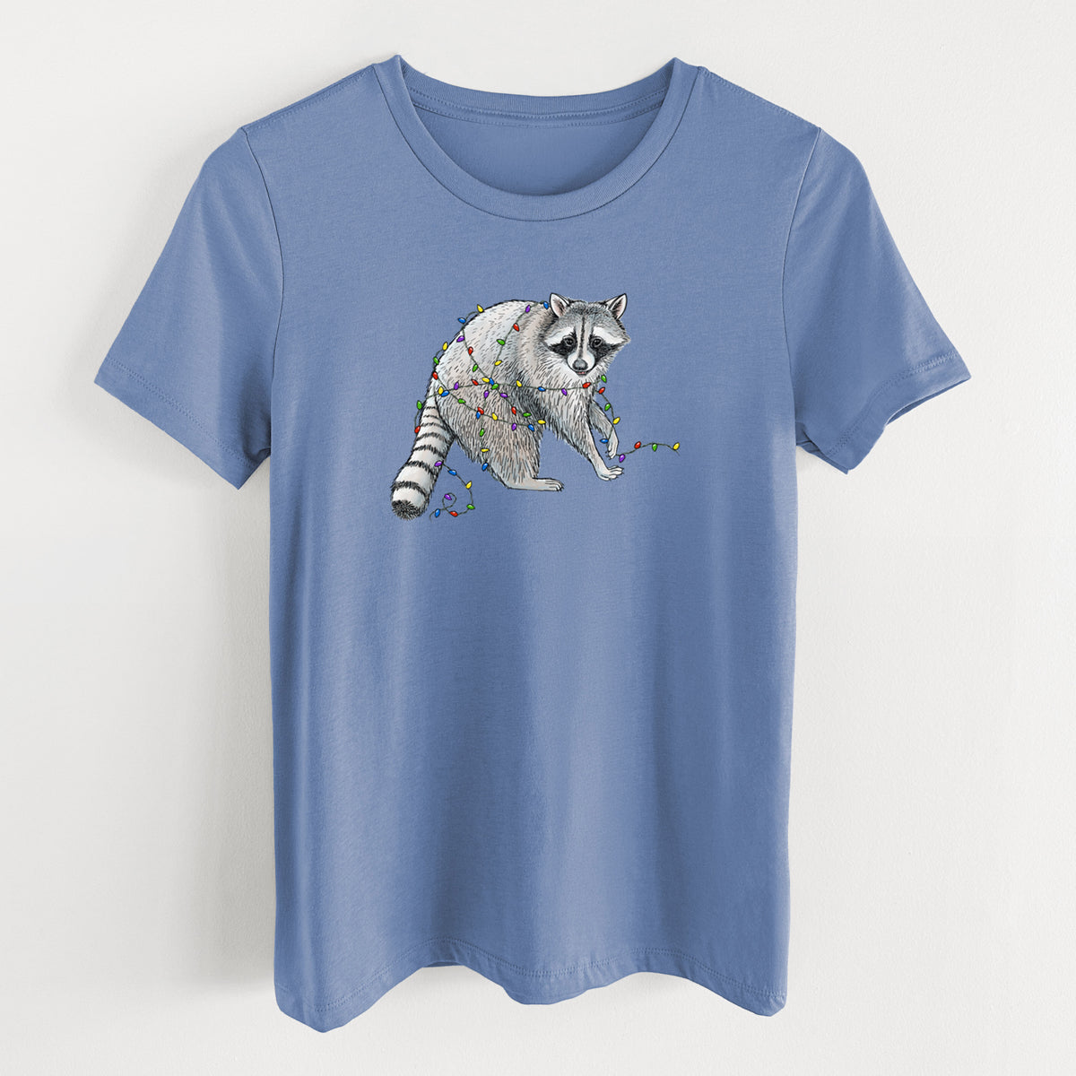 Blue bell women's relaxed fit cotton t-shirt laid flat, printed with a black ink raccoon tangled in a string of colorful holiday lights.