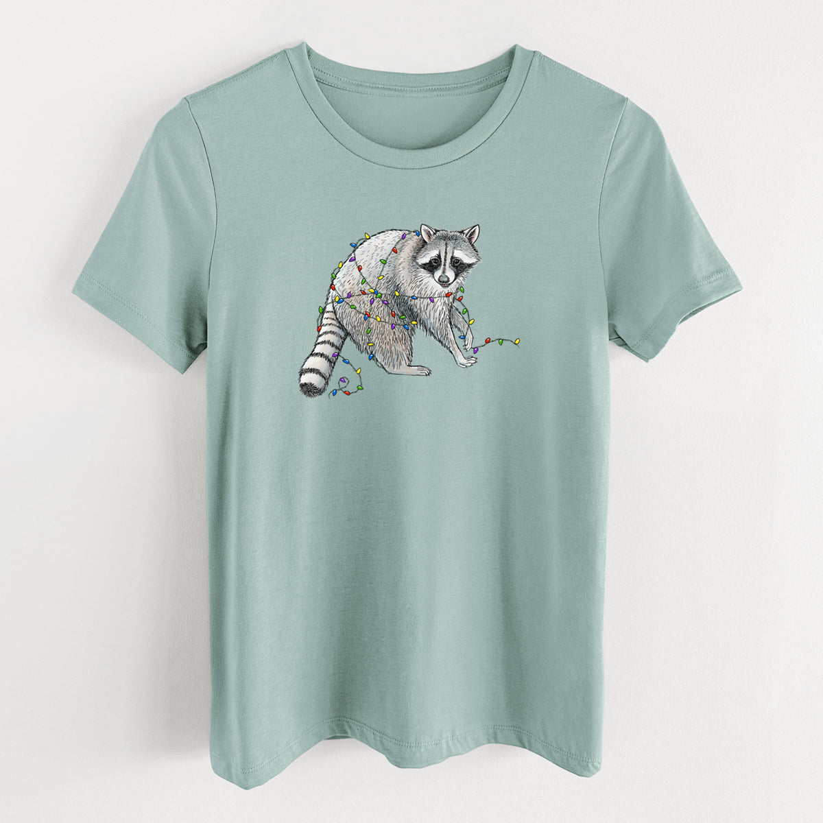 Dusty blue women's relaxed fit cotton t-shirt laid flat, printed with a black ink raccoon tangled in a string of colorful holiday lights.