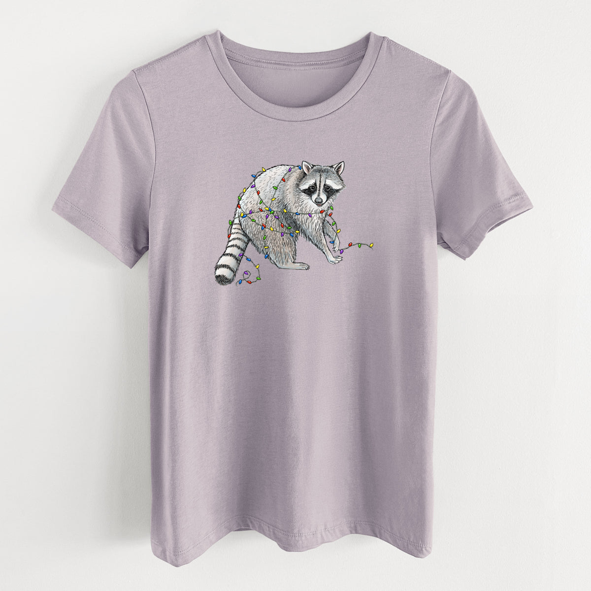 Light violet women's relaxed fit cotton t-shirt laid flat, printed with a black ink raccoon tangled in a string of colorful holiday lights.