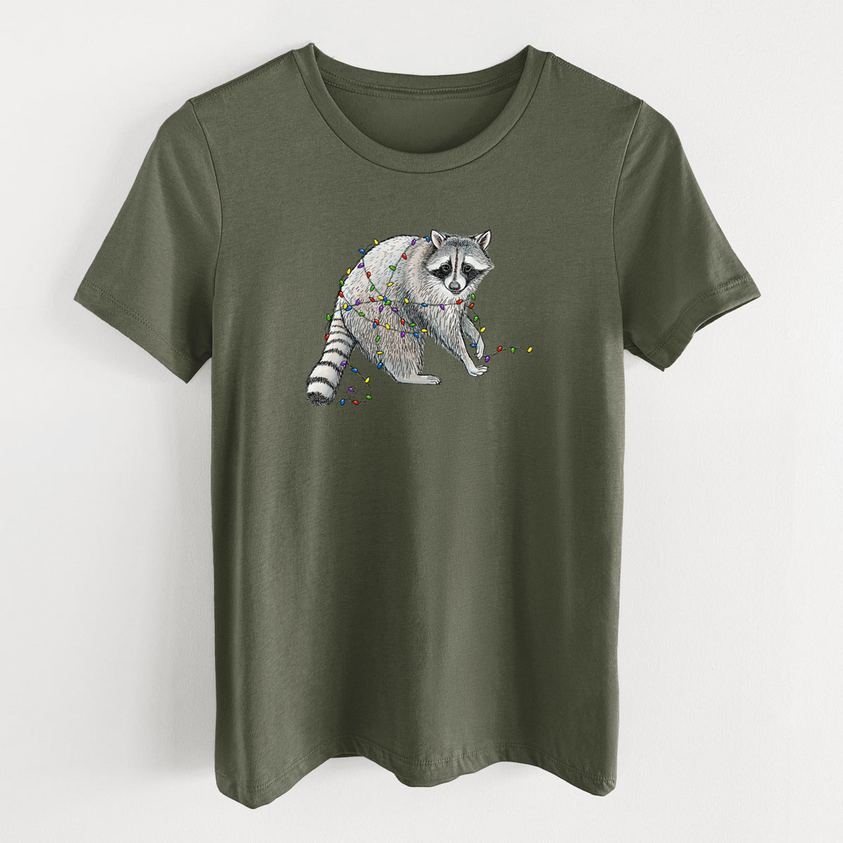 Military green women's relaxed fit cotton t-shirt laid flat, printed with a black ink raccoon tangled in a string of colorful holiday lights.