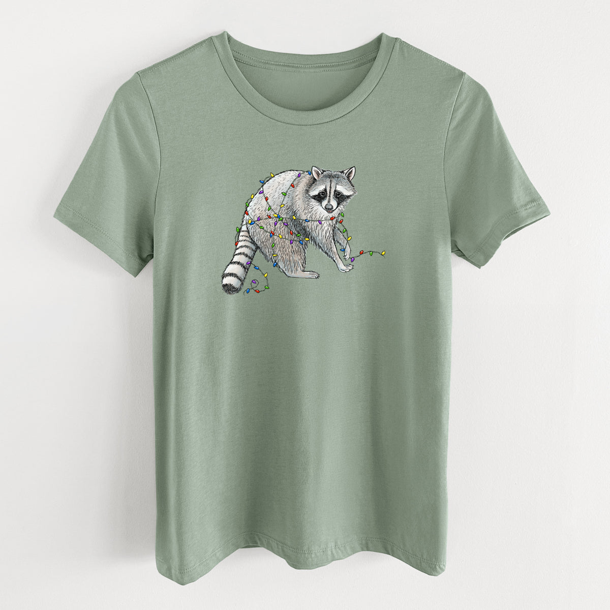 Sage green women's relaxed fit cotton t-shirt laid flat, printed with a black ink raccoon tangled in a string of colorful holiday lights.