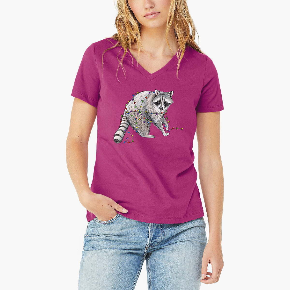 Woman wearing a berry pink women's relaxed fit cotton V-neck t-shirt printed with a black ink raccoon tangled in a string of colorful holiday lights.