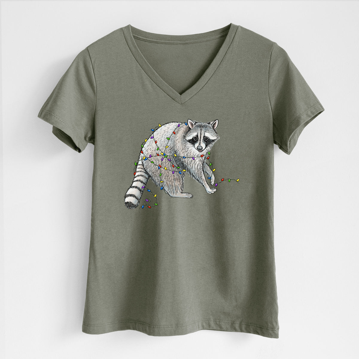 Military green women's relaxed fit cotton V-neck t-shirt laid flat, printed with a black ink raccoon tangled in a string of colorful holiday lights.