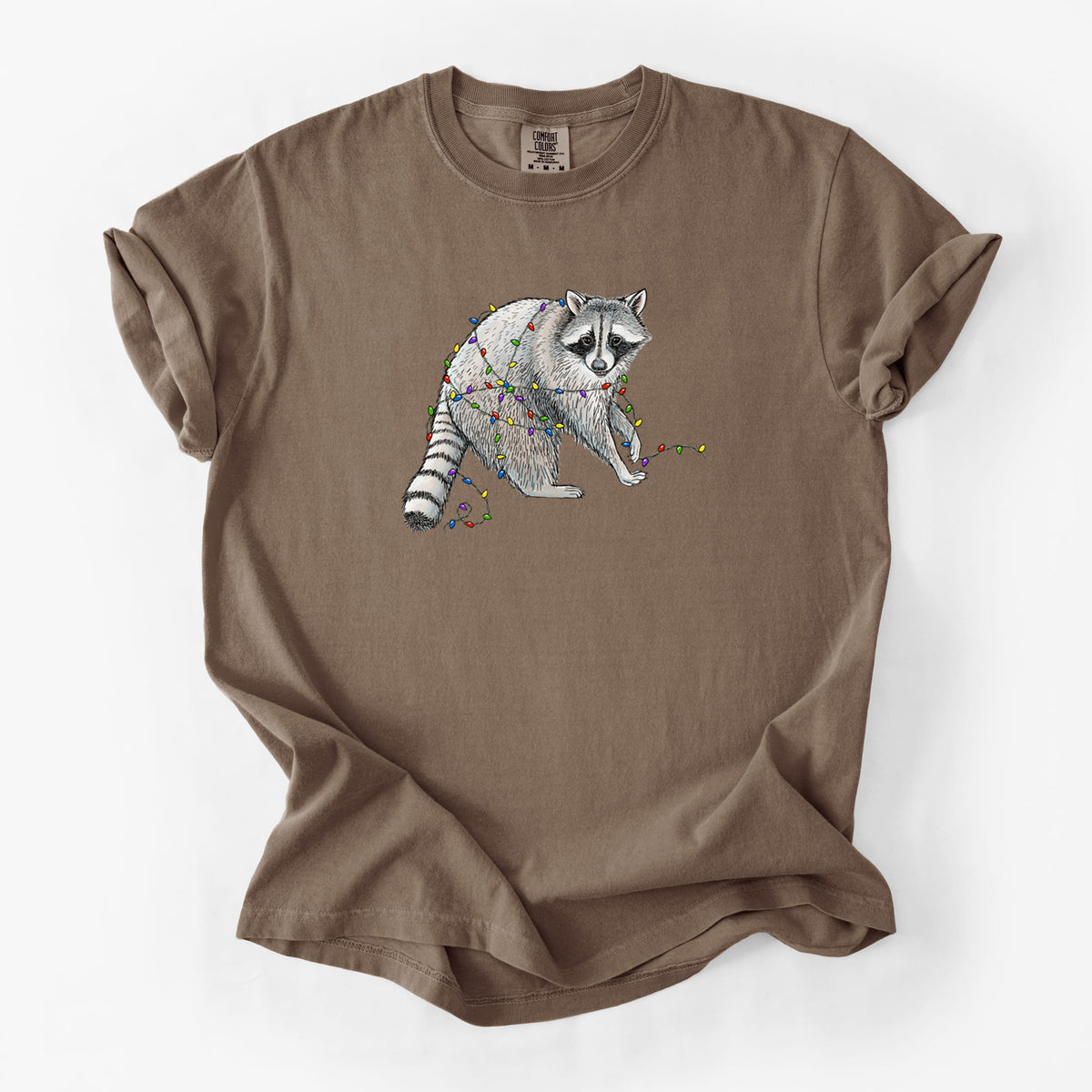 Espresso brown Comfort Colors t-shirt laid flat, printed with a black ink raccoon tangled in a string of colorful holiday lights.