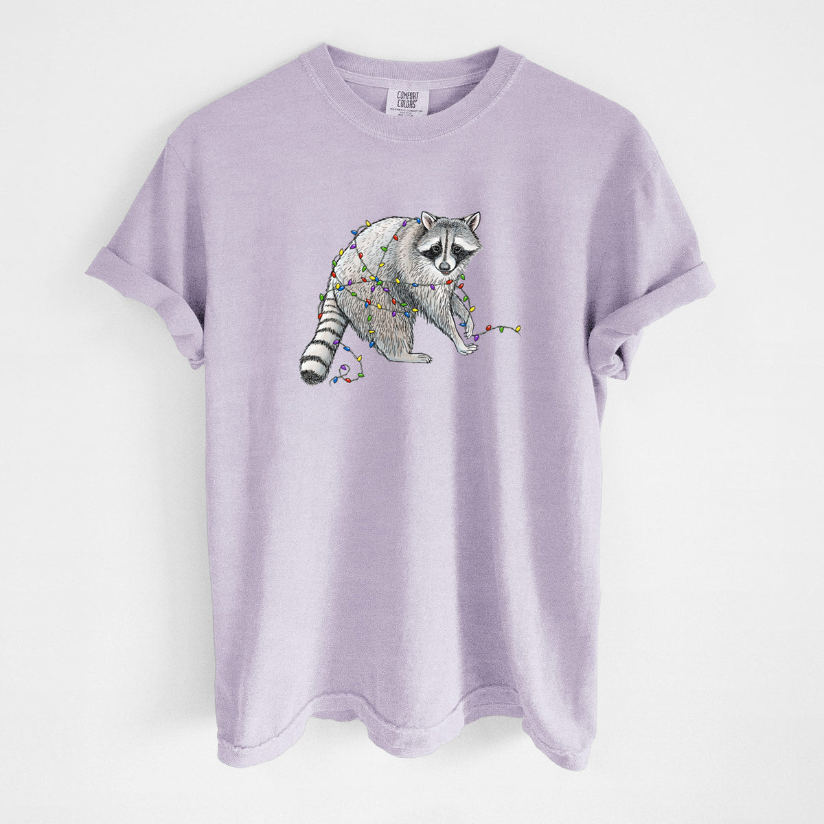 Orchid purple Comfort Colors t-shirt laid flat, printed with a black ink raccoon tangled in a string of colorful holiday lights.