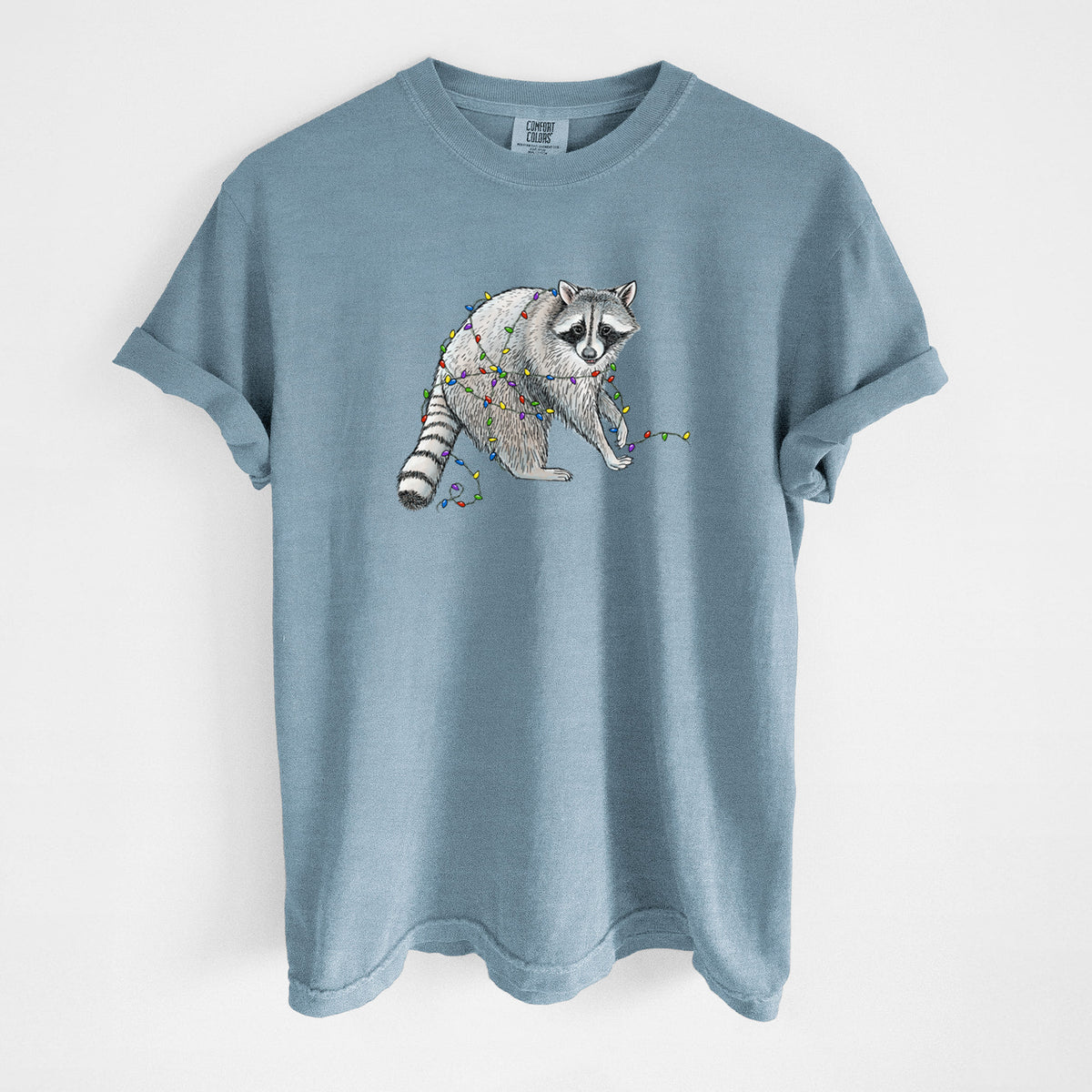 Steel blue Comfort Colors t-shirt laid flat, printed with a black ink raccoon tangled in a string of colorful holiday lights.