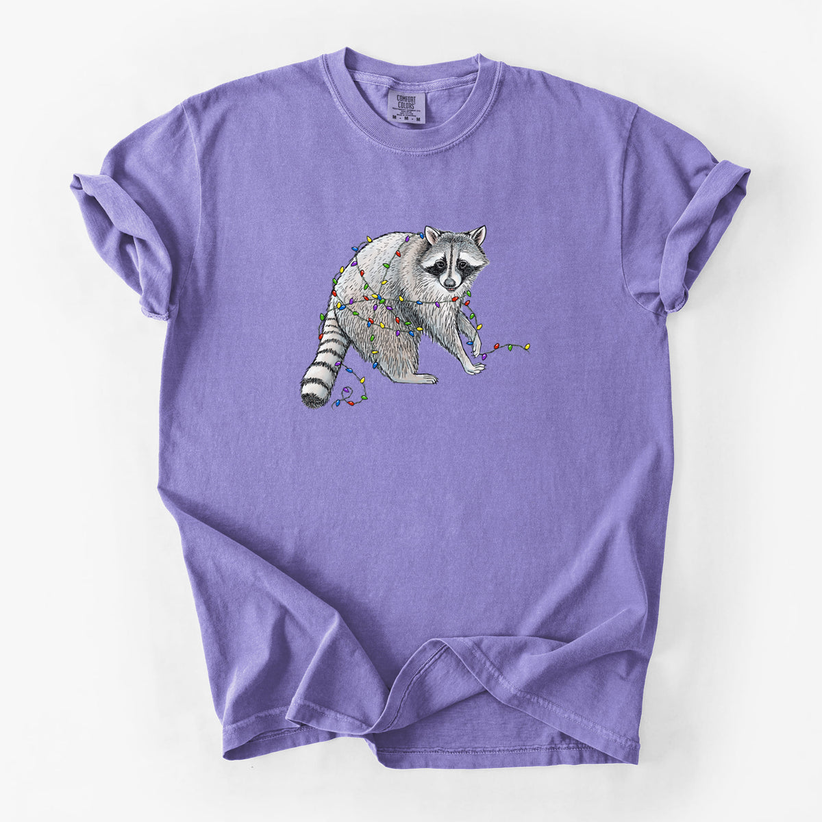 Violet purple Comfort Colors t-shirt laid flat, printed with a black ink raccoon tangled in a string of colorful holiday lights.