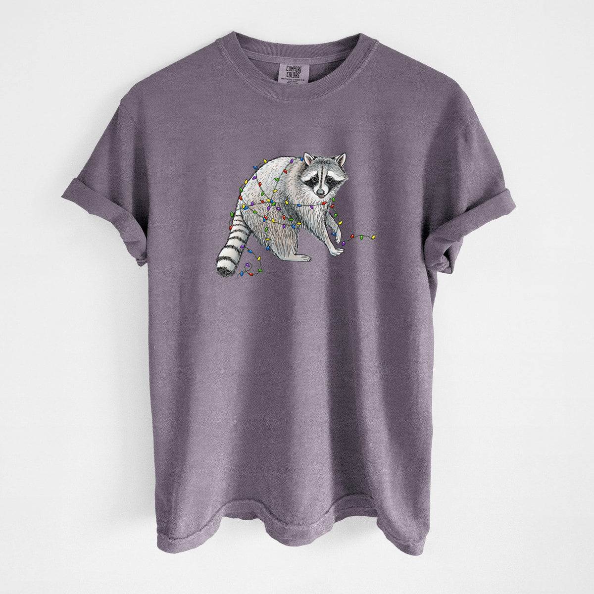 Wine red Comfort Colors t-shirt laid flat, printed with a black ink raccoon tangled in a string of colorful holiday lights.