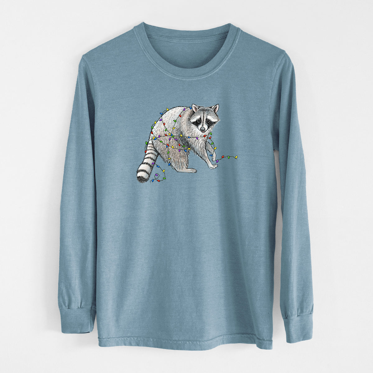 Steel blue Comfort Colors long sleeve shirt laid flat, printed with a black ink raccoon tangled in a string of colorful holiday lights.