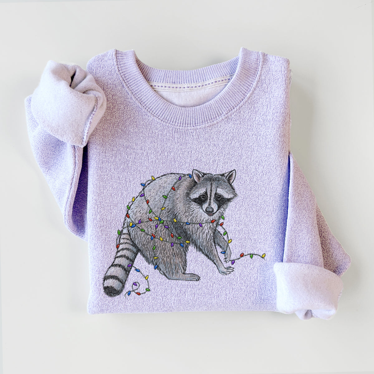 Ice purple knit sweatshirt printed with a black ink raccoon tangled in a string of colorful holiday lights, styled flat.