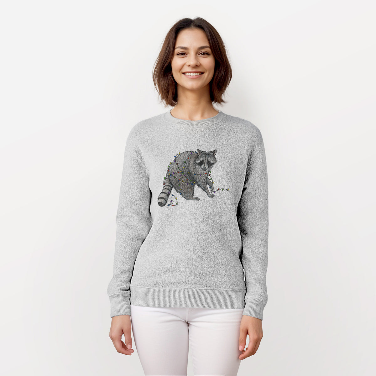 Woman wearing a knit sweatshirt printed with a black ink raccoon tangled in a string of colorful holiday lights.