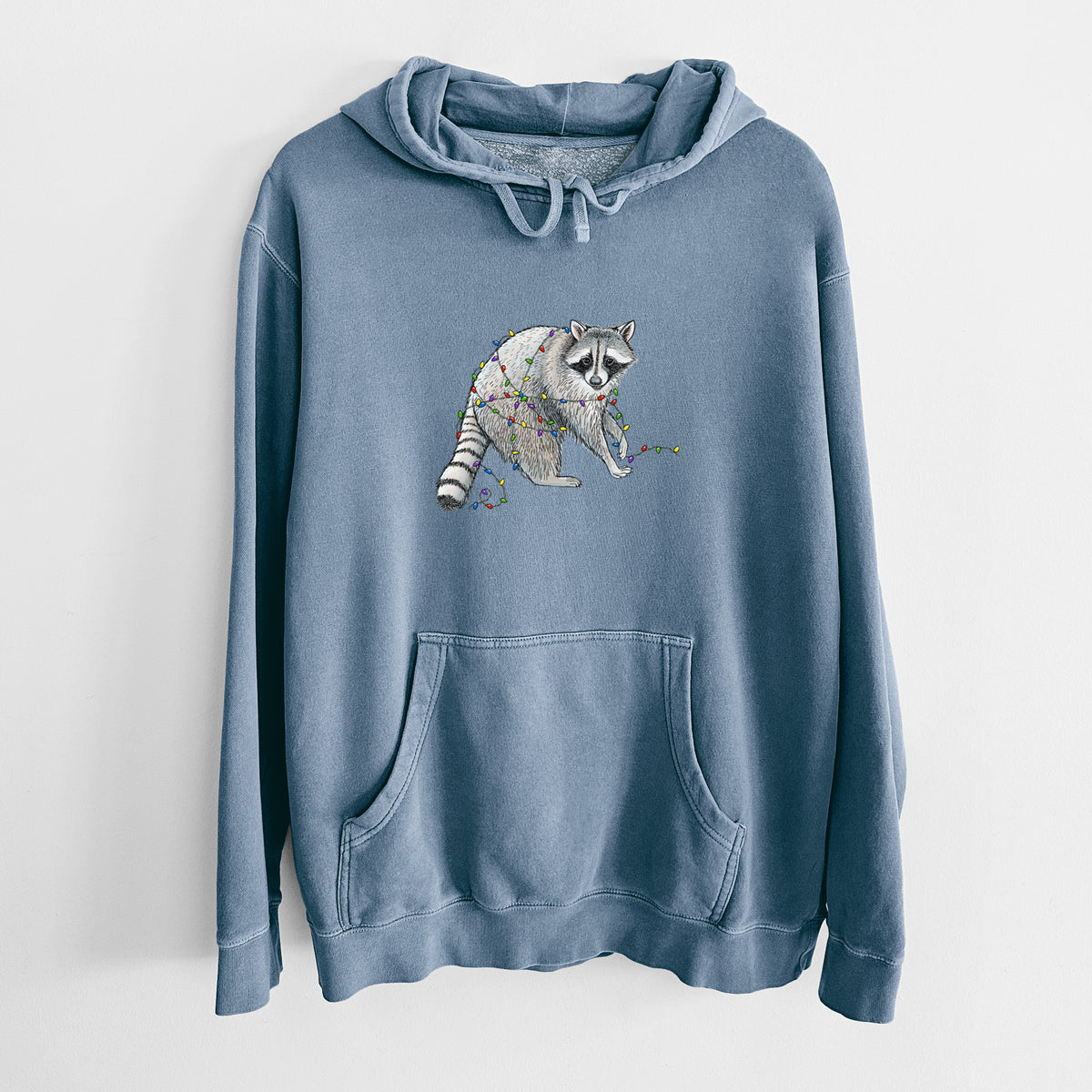 Slate blue pigment dyed hoodie laid flat, printed with a black ink raccoon tangled in a string of colorful holiday lights.
