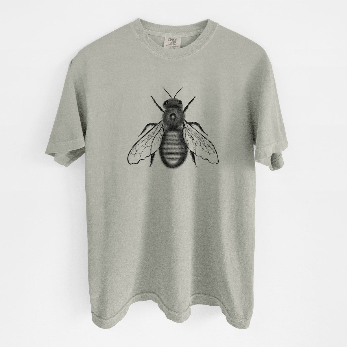 Sandstone beige Comfort Colors t-shirt laid flat, printed with a detailed black ink illustration of an eastern carpenter bee with its wings spread, seen from above.