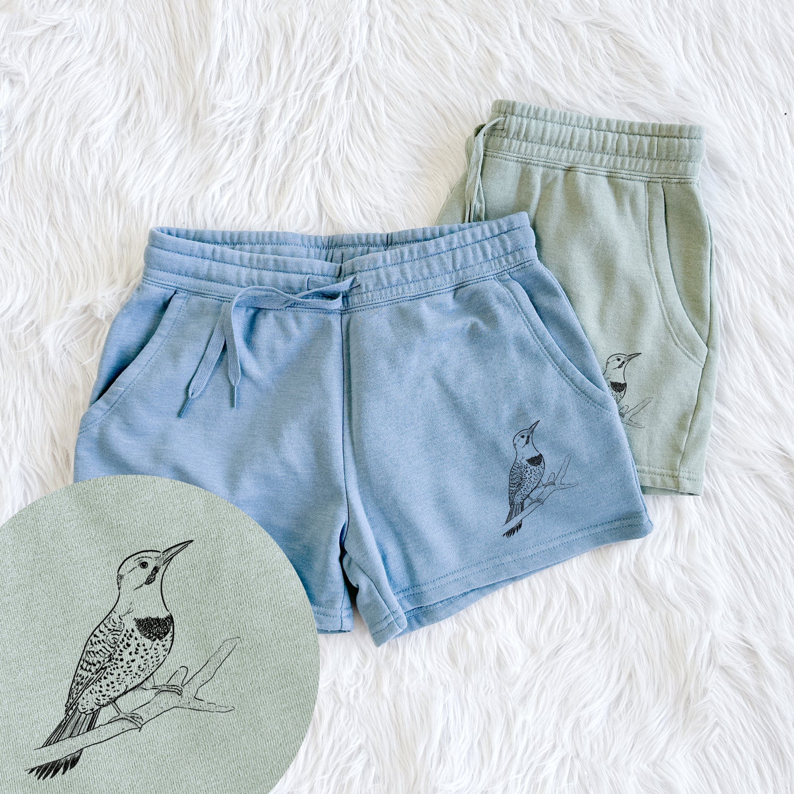 Two pairs of Cali Wave shorts in different colors printed with a detailed black ink illustration of a yellow-shafted northern flicker perched on a branch, with a close-up of the print.