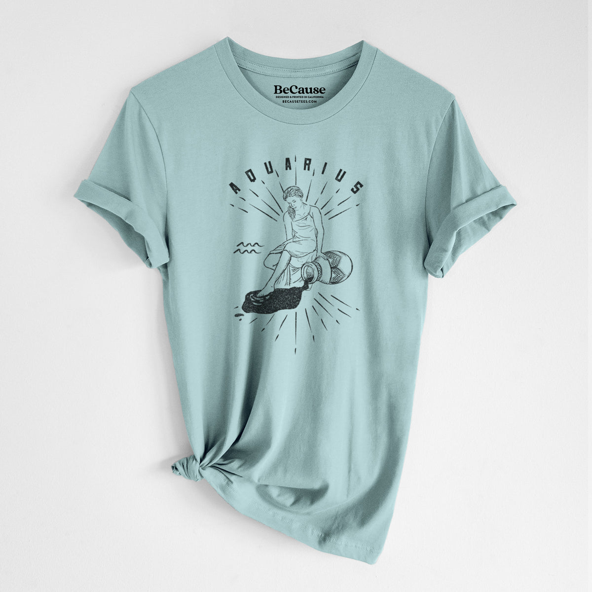 Dusty blue lightweight cotton t-shirt laid flat with the sleeves rolled, printed with a black ink figure pouring water with the word Aquarius, for the Aquarius zodiac sign.