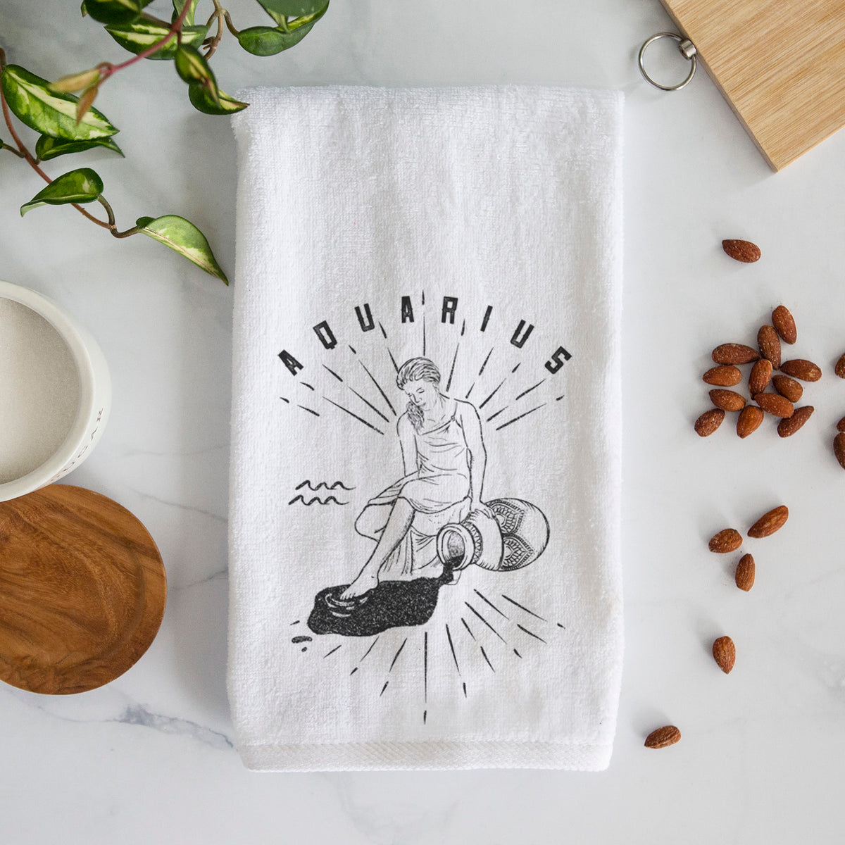 White hand towel printed with a black ink figure pouring water with the word Aquarius, for the Aquarius zodiac sign.