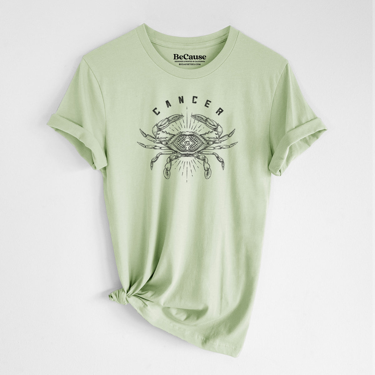 Spring green lightweight cotton t-shirt laid flat with the sleeves rolled, printed with a black ink crab with the word Cancer, for the Cancer zodiac sign.