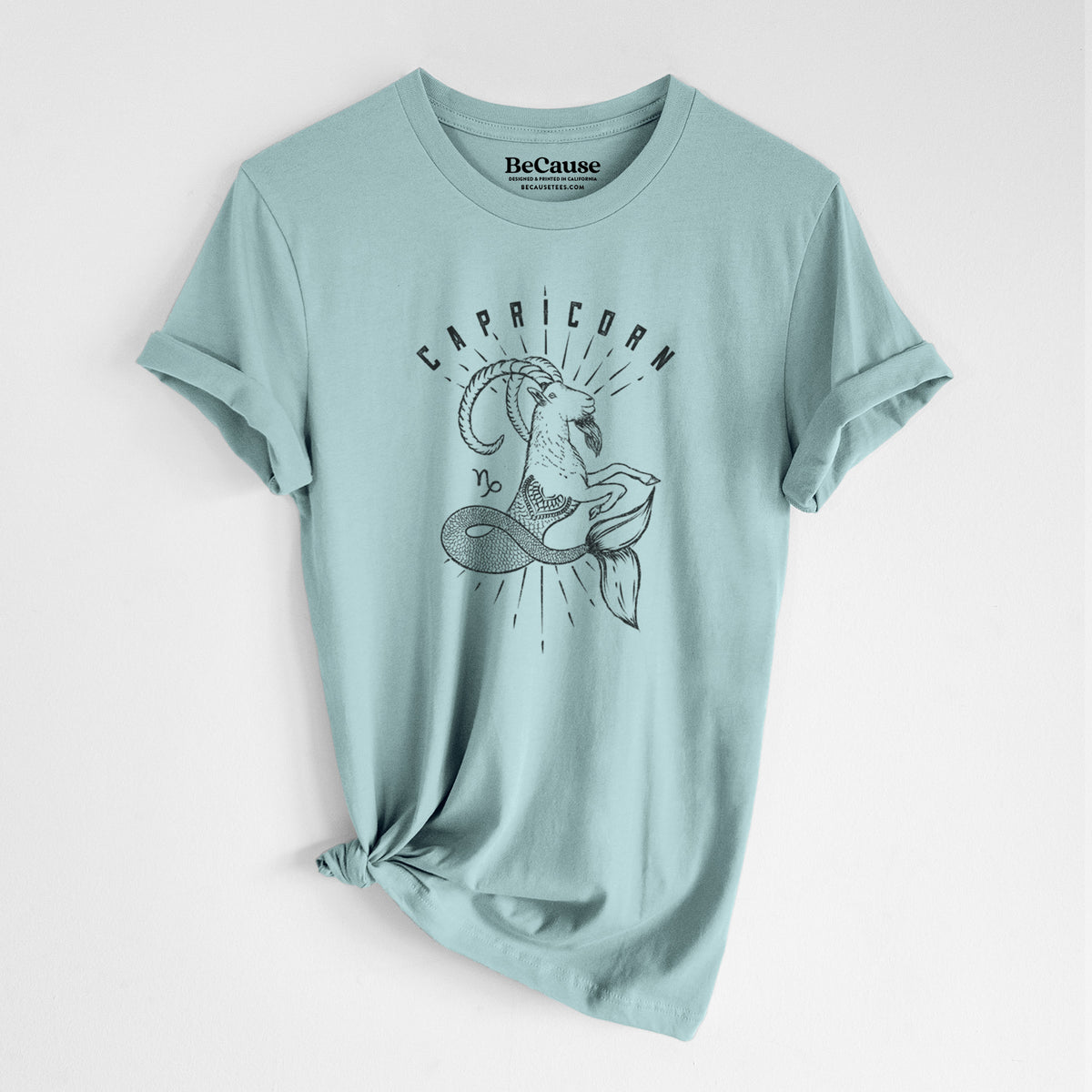 Dusty blue lightweight cotton t-shirt laid flat with the sleeves rolled, printed with a black ink sea-goat with the word Capricorn, for the Capricorn zodiac sign.