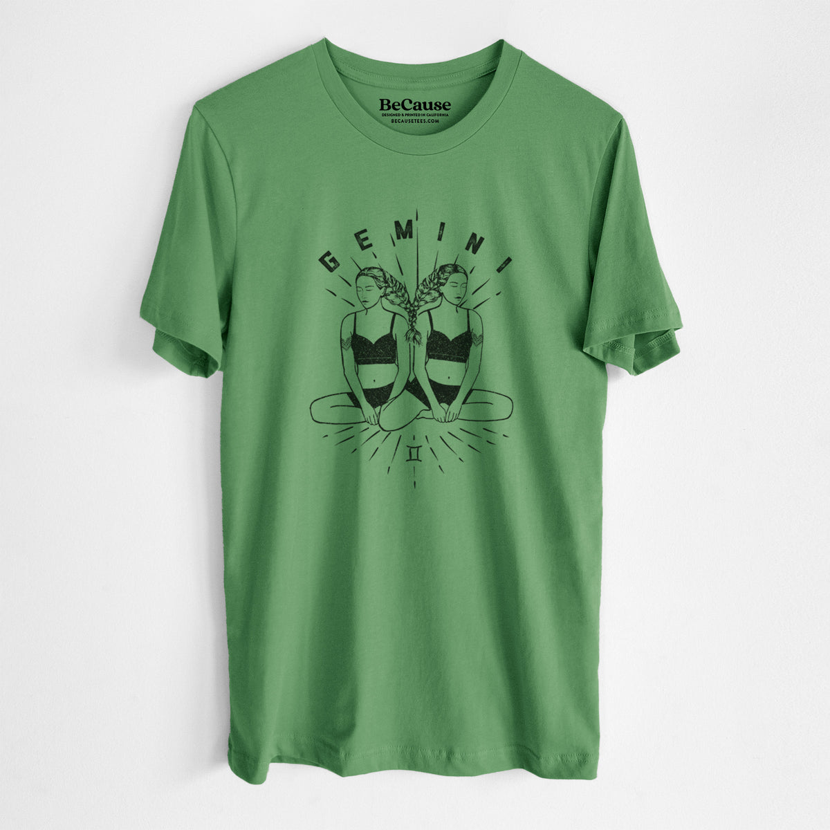 Leaf green lightweight cotton t-shirt laid flat, printed with black ink twin women sitting back to back with the word Gemini, for the Gemini zodiac sign.