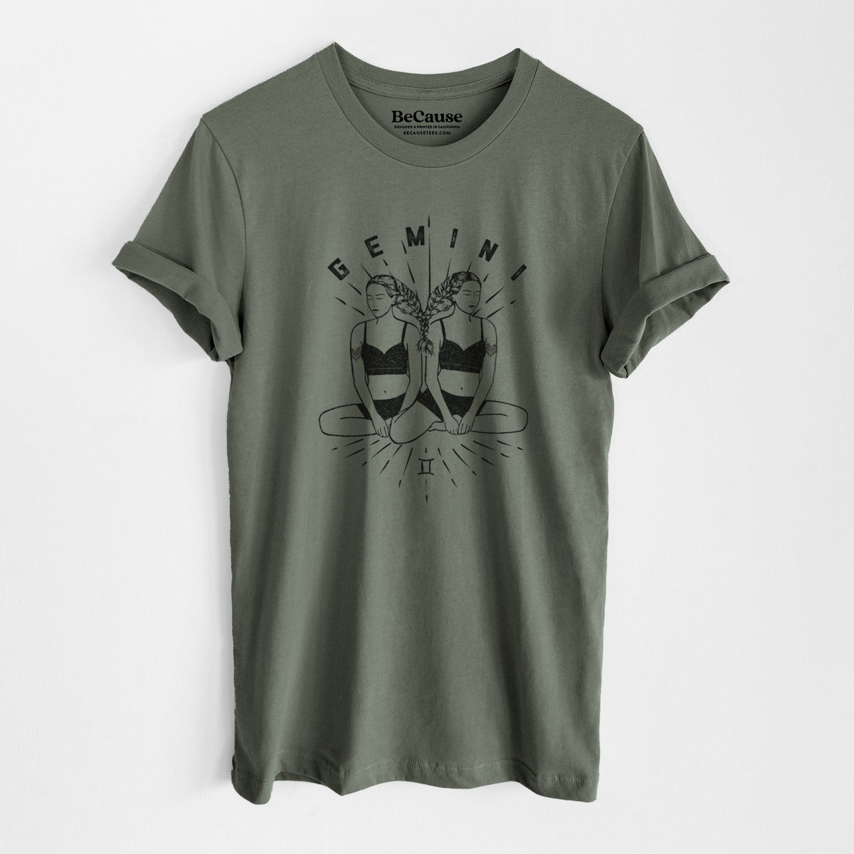 Military green lightweight cotton t-shirt laid flat, printed with black ink twin women sitting back to back with the word Gemini, for the Gemini zodiac sign.