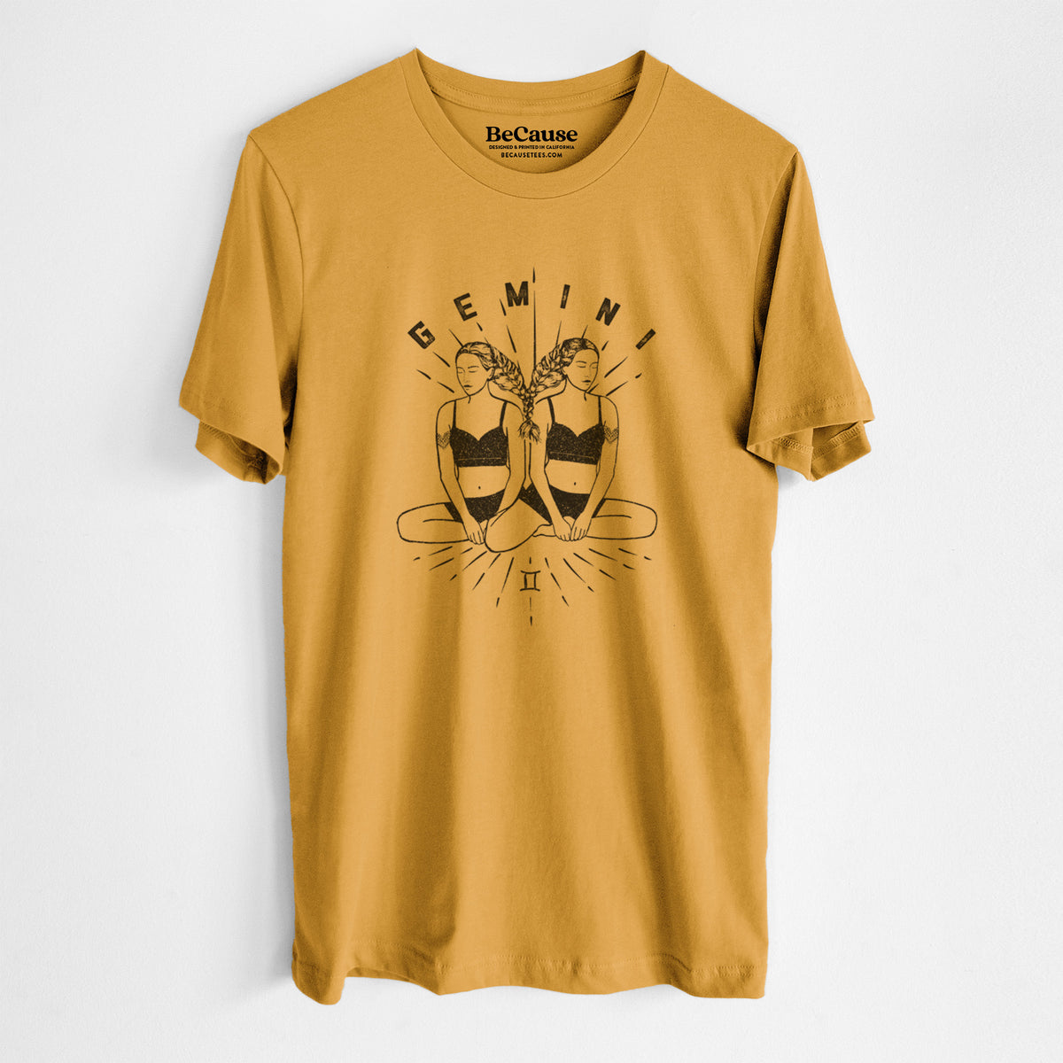 Mustard yellow lightweight cotton t-shirt laid flat, printed with black ink twin women sitting back to back with the word Gemini, for the Gemini zodiac sign.