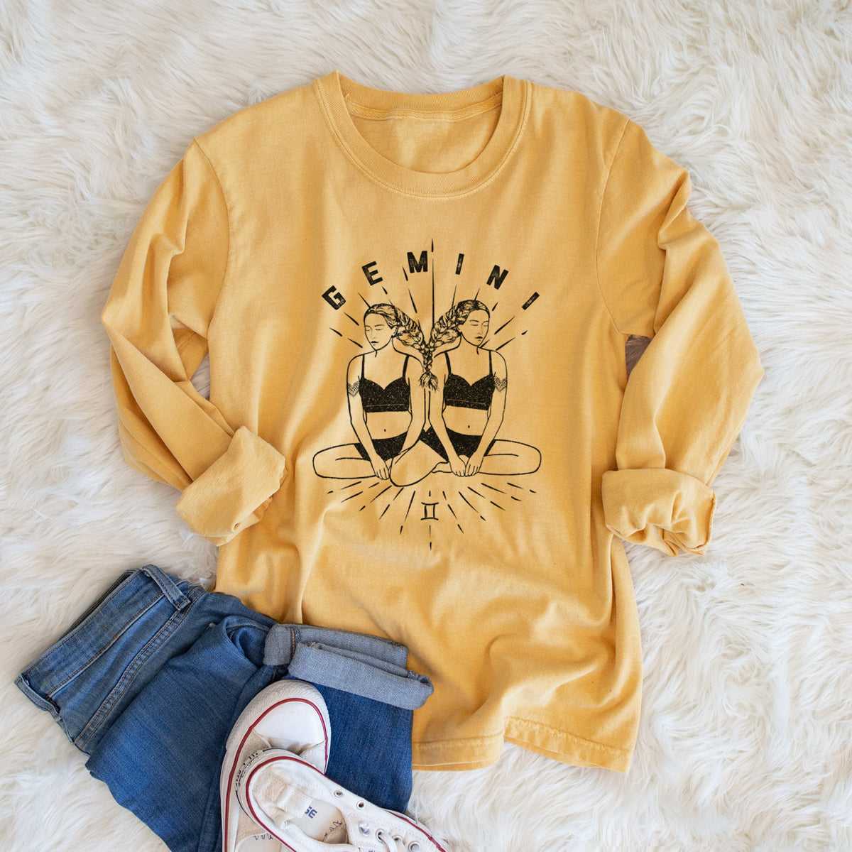 Golden wheat yellow Comfort Colors long sleeve shirt printed with black ink twin women sitting back to back with the word Gemini, for the Gemini zodiac sign, shown in a lifestyle photo.