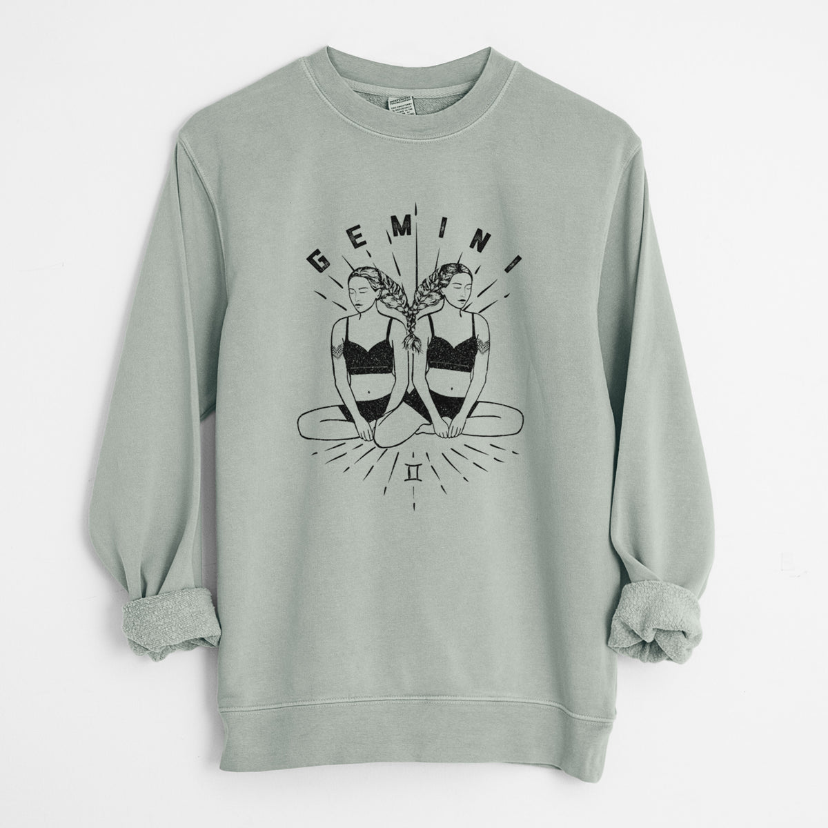 Sage green pigment dyed crewneck sweatshirt laid flat with the sleeves rolled, printed with black ink twin women sitting back to back with the word Gemini, for the Gemini zodiac sign.