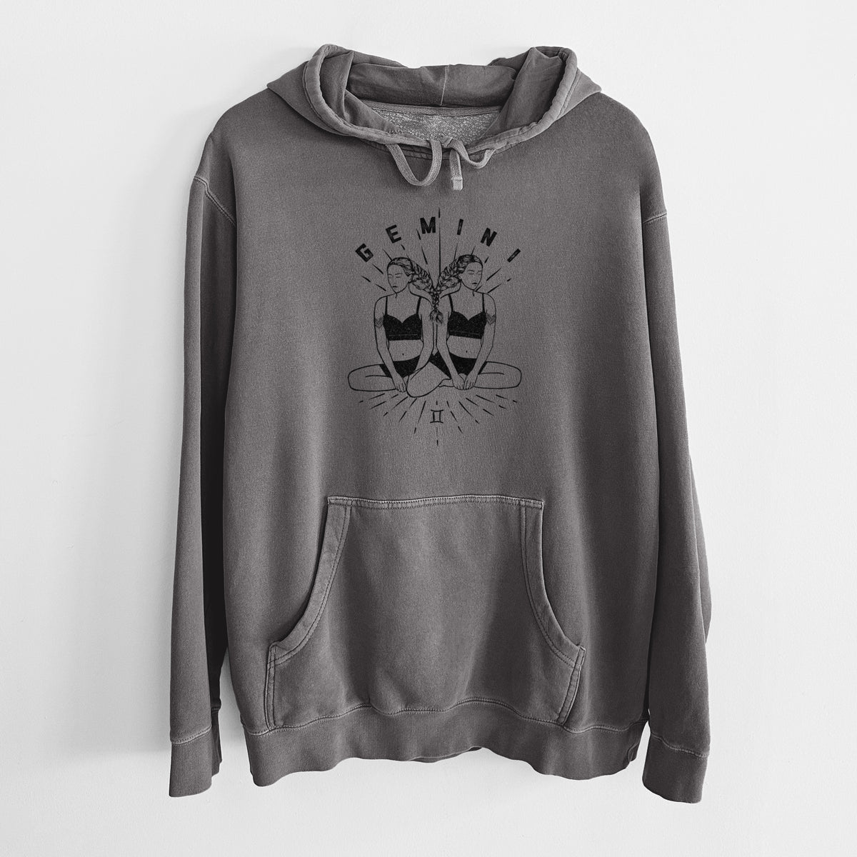 Faded black pigment dyed hoodie laid flat, printed with black ink twin women sitting back to back with the word Gemini, for the Gemini zodiac sign.