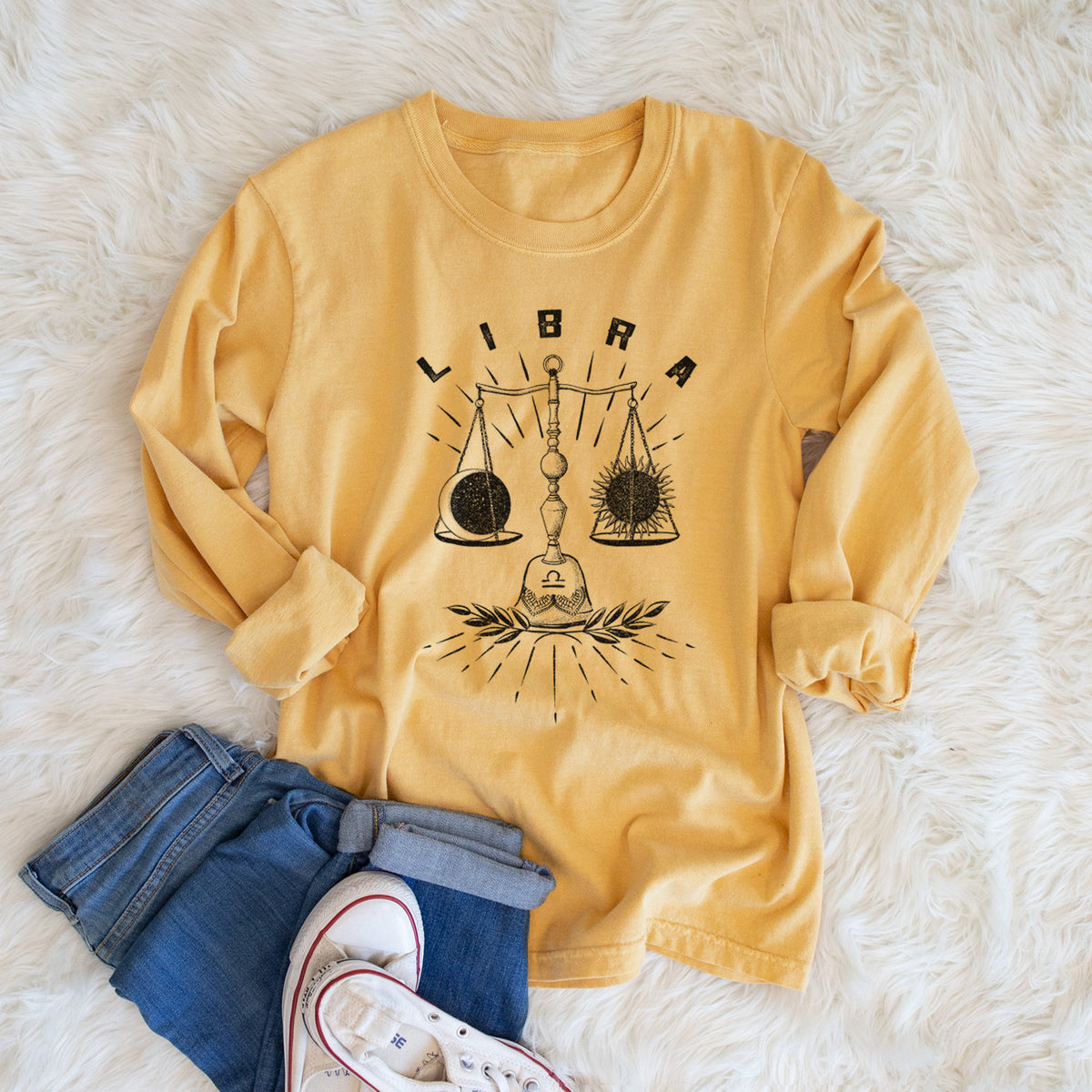 Golden wheat yellow Comfort Colors long sleeve shirt printed with a black ink set of balance scales with the word Libra, for the Libra zodiac sign, shown in a lifestyle photo.