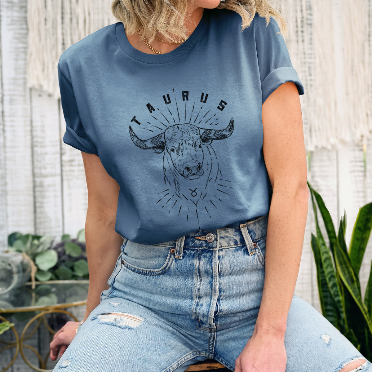 Woman wearing a steel blue lightweight cotton t-shirt printed with a black ink bull's head with the word Taurus, for the Taurus zodiac sign.