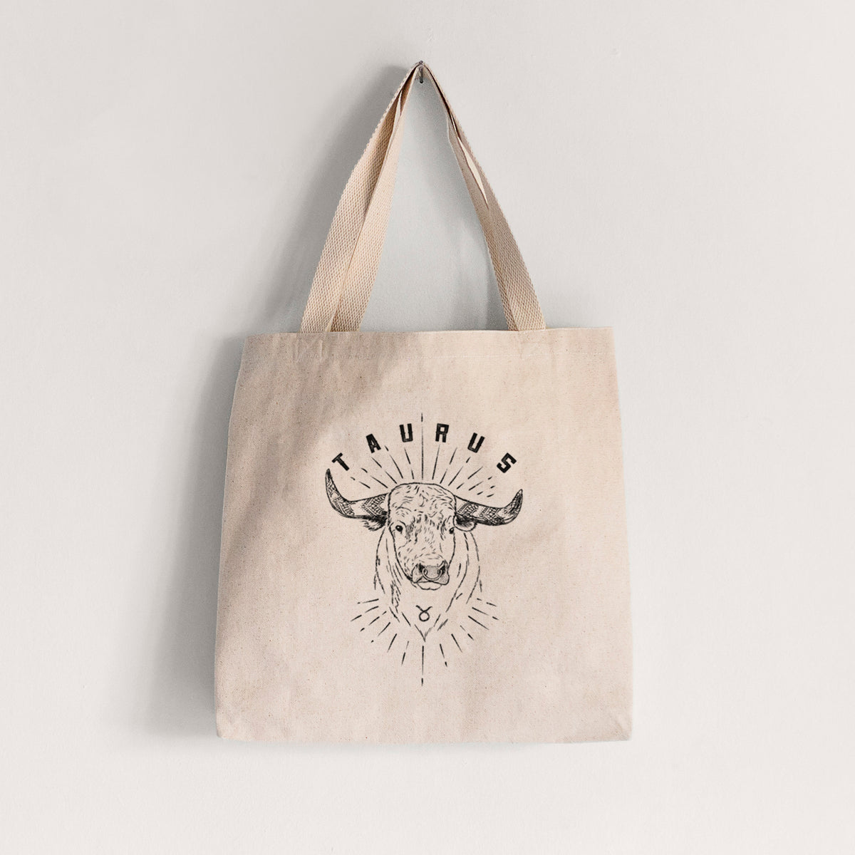 Natural canvas tote bag printed with a black ink bull's head with the word Taurus, for the Taurus zodiac sign.