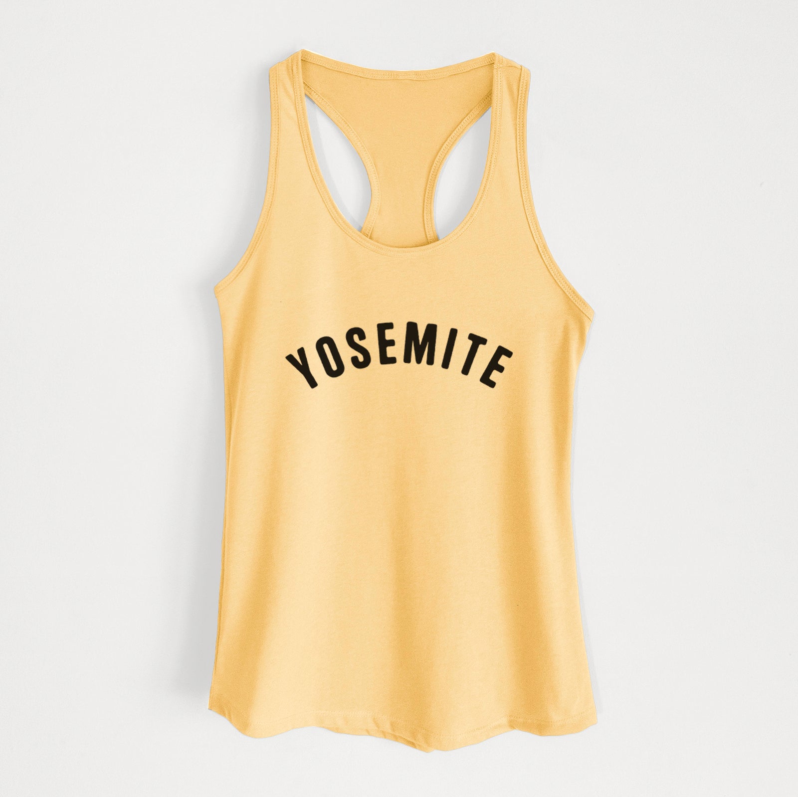 Banana cream women's racerback tank top laid flat, printed with the word Yosemite in bold black letters arched across the chest.