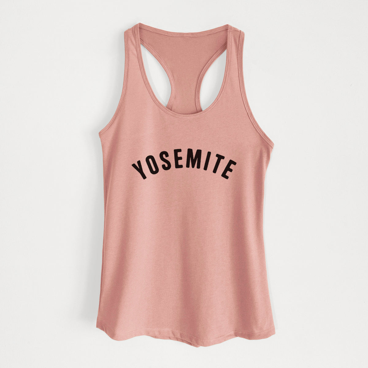 Desert pink women's racerback tank top laid flat, printed with the word Yosemite in bold black letters arched across the chest.