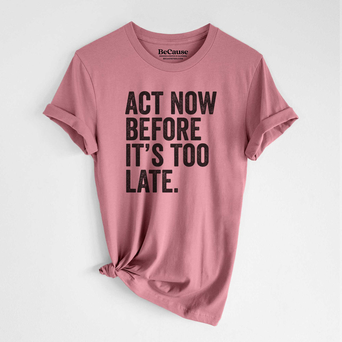 Mauve pink lightweight cotton t-shirt laid flat with the sleeves rolled, printed with bold black words reading Act Now Before It's Too Late.