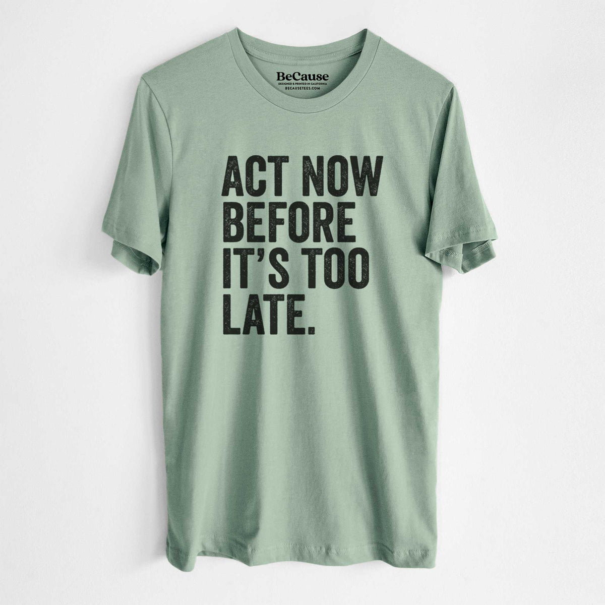 Sage green lightweight cotton t-shirt laid flat, printed with bold black words reading Act Now Before It's Too Late.