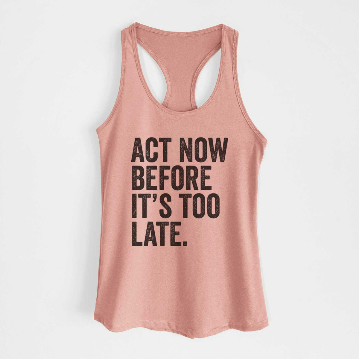 Desert pink women's racerback tank top laid flat, printed with bold black words reading Act Now Before It's Too Late.