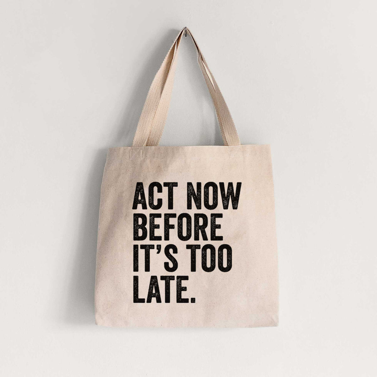 Natural canvas tote bag printed with bold black words reading Act Now Before It's Too Late.