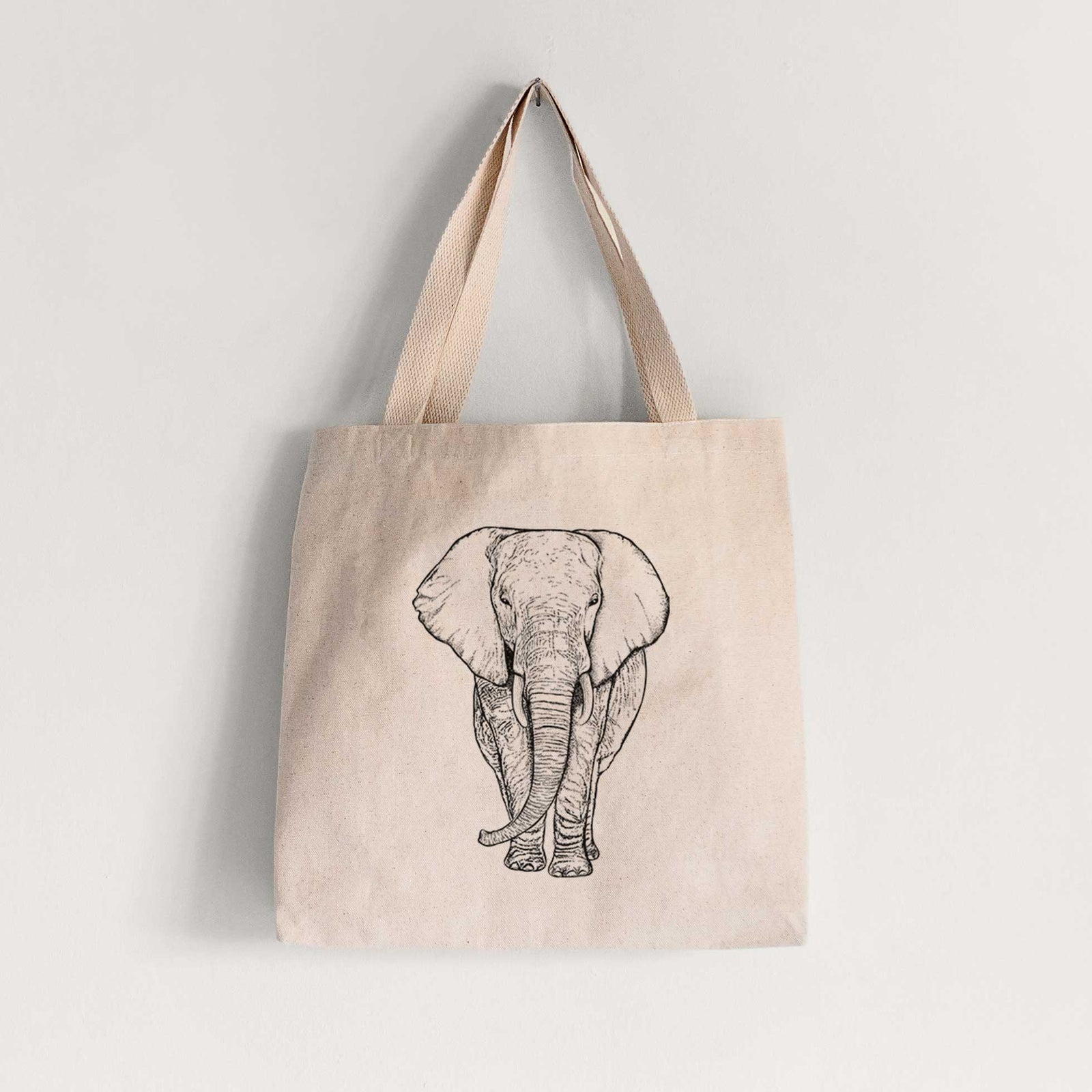 Natural canvas tote bag printed with a black ink line drawing of an African elephant facing forward with large ears and tusks.