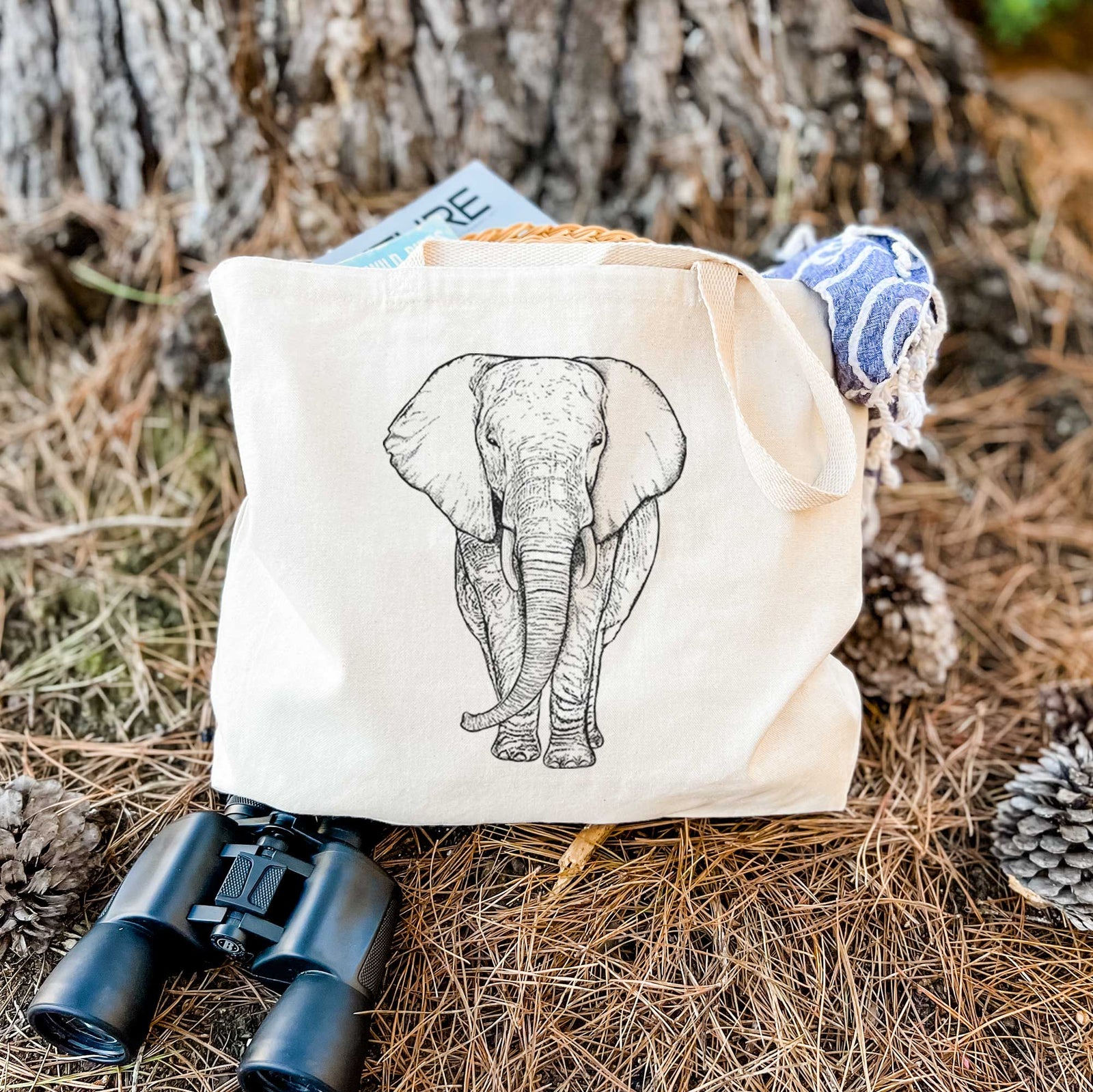 Natural canvas tote bag printed with a black ink line drawing of an African elephant facing forward with large ears and tusks.