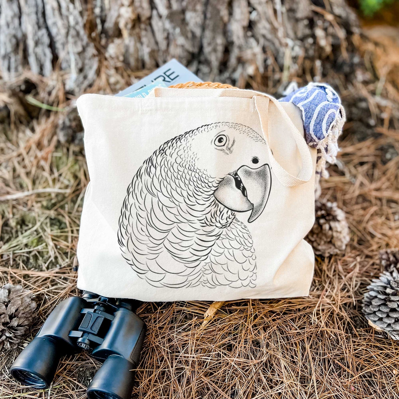 Natural canvas tote bag printed with a detailed black ink portrait of an African grey parrot's head.