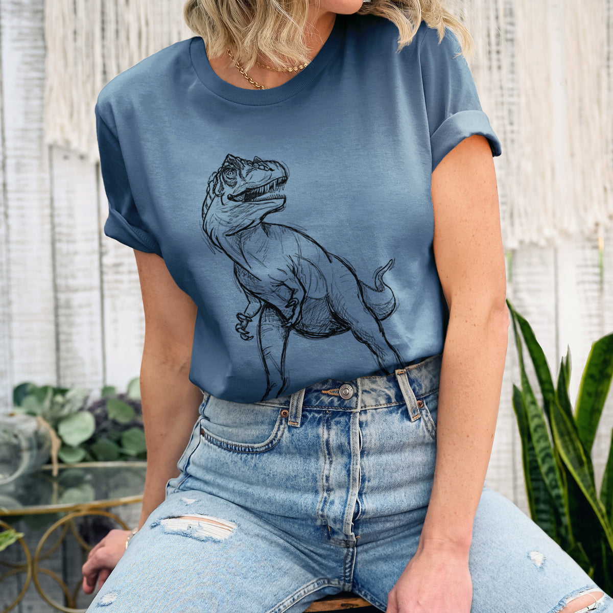 Woman wearing a steel blue lightweight cotton t-shirt printed with a black ink illustration of an Allosaurus walking.