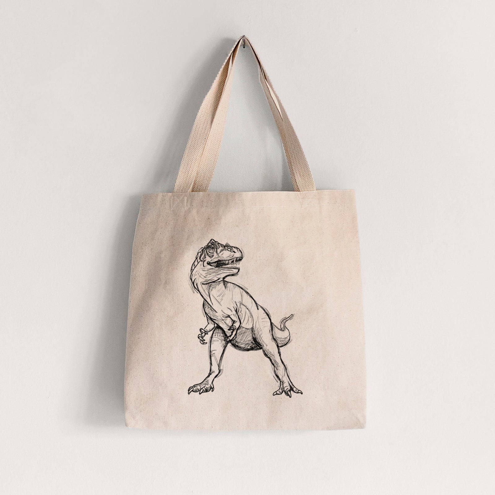 Natural canvas tote bag printed with a black ink illustration of an Allosaurus walking.