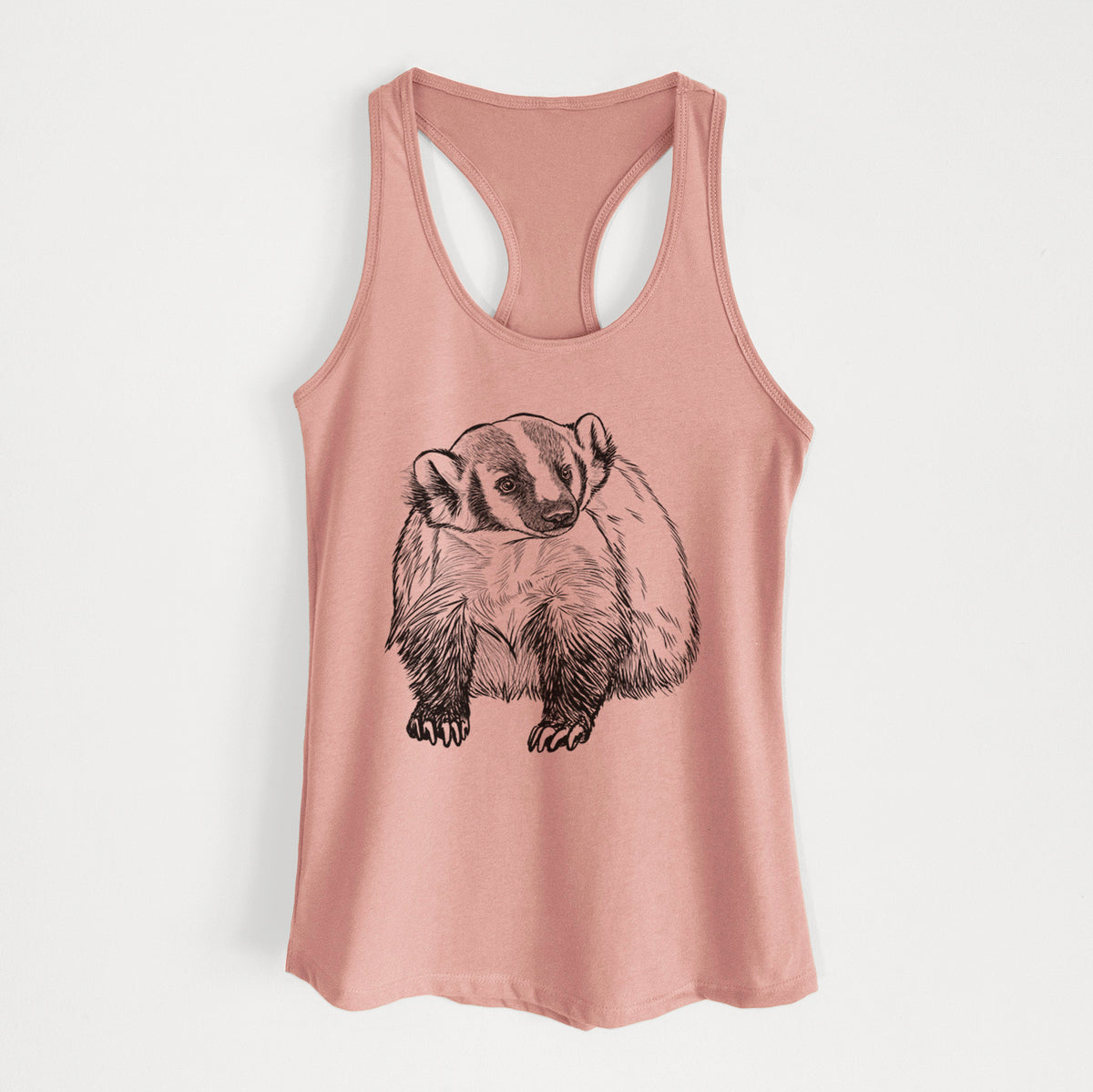 Desert pink women's racerback tank top laid flat, printed with a detailed black ink illustration of an American badger facing forward.