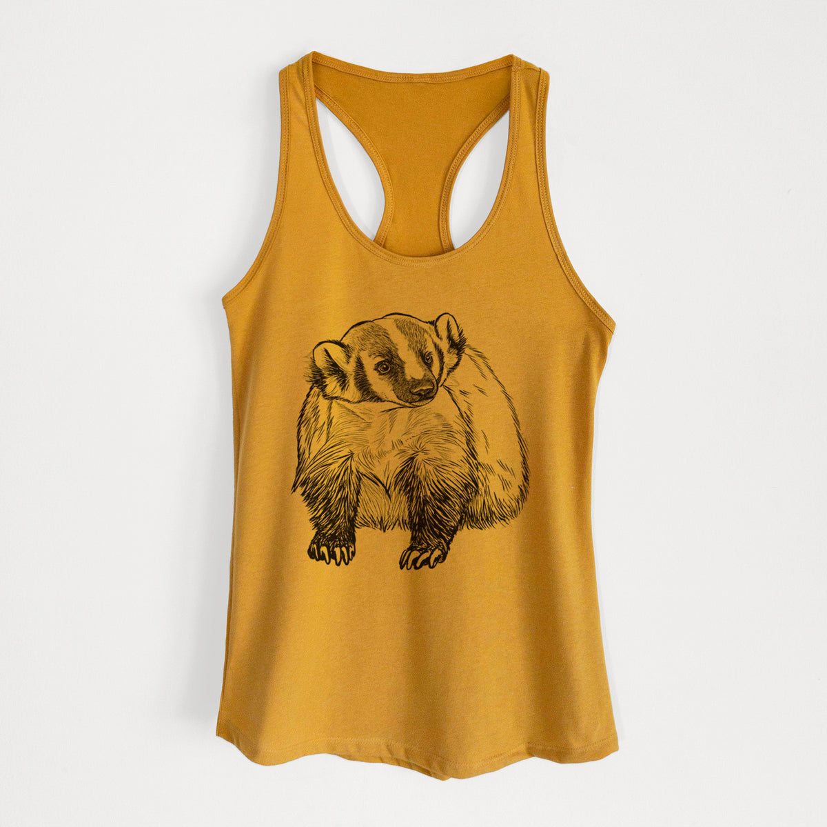 Gold women's racerback tank top laid flat, printed with a detailed black ink illustration of an American badger facing forward.